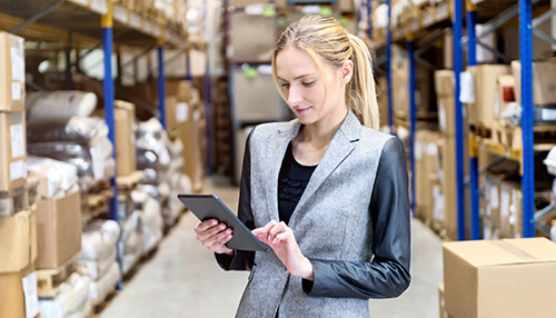 Businesswoman managing inventory on a tablet in a warehouse, checking stock levels and preparing to sell an ecommerce business Update your inventory to sell your ecommerce business