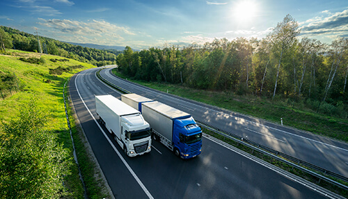 What are the risks when driving near trucks Two trucks driving side by side on a highway, representing the trucking industry and the potential risks of truck accidents on the road.