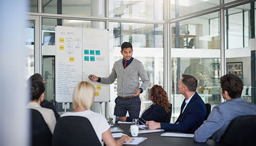 Assign assignments and roles A group of professionals in a meeting, discussing strategies for running and growing an online business with a focus on planning and collaboration.