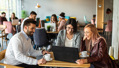 Better workplace conditions A cheerful team productivity of three individuals working together in a café, sharing ideas over a laptop and coffee