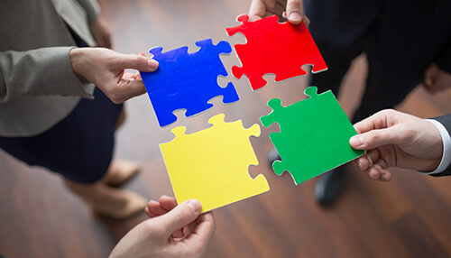 Collaborative setting Business professionals holding four colorful puzzle pieces symbolizing teamwork and collaboration.