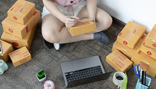 Custom boxes with logos Person preparing wholesale custom packaging for products while organizing and labeling boxes in a home office setting