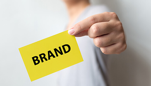 Enhance your brand image Person holding a brand card, symbolizing the importance of market research in establishing and refining brand identity.