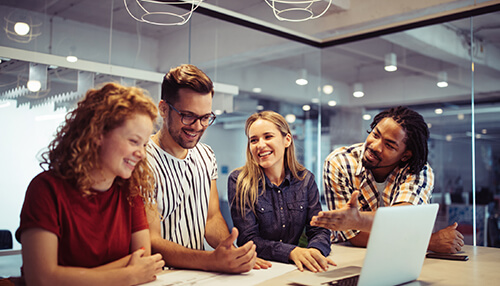 Smiling team members engaged in a lively discussion around a laptop, reflecting open communication and a positive work environment Give employees the space they require to encourage a positive work environment