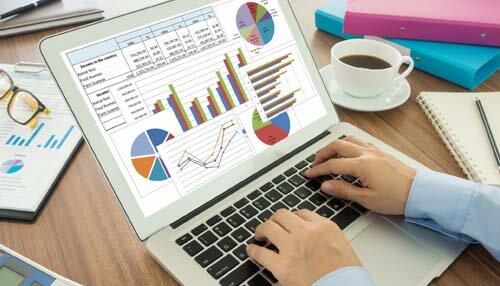 Learn the fundamentals of business analysis - tycoonstory | tycoonstory media Person analyzing financial charts and graphs on a laptop as part of their journey to become a business analyst, with data visualizations and reports on the screen, accompanied by coffee and office supplies in the background