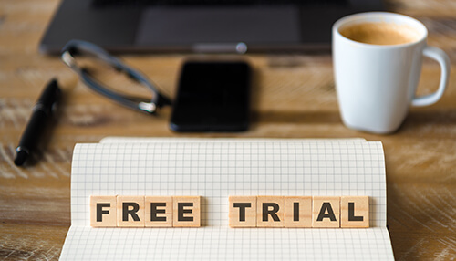 Offer a free trial Wooden letter blocks spelling "free trial" resting on an open notebook, depicting a common strategy used in lead generation to attract potential customers.