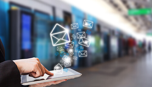 Send individualized emails A person using a tablet with digital mail icons floating above, symbolizing modern communication and booking for luxury resorts.