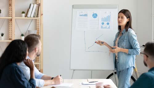 Sharpening communication skills - tycoonstory | tycoonstory media Professional presenting data insights on a whiteboard to colleagues as part of a training session on how to become a business analyst, highlighting trends and making data-driven recommendations.