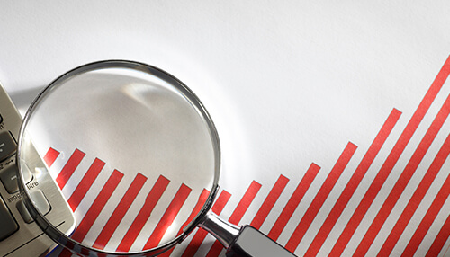 Streamline competitive analysis A magnifying glass over a graph with red bars, illustrating analysis and insights related to business intelligence and data trends.