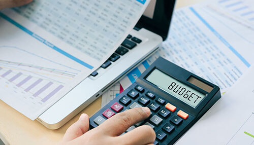 Budgeting strategy - tycoonstory | tycoonstory media Budget analysis for your business with hands using a calculator to evaluate expenses, revenue data, and financial planning documents.