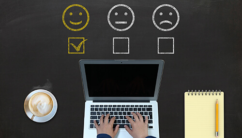 Customer feedback questions - tycoonstory | tycoonstory media Person typing on a laptop with customer feedback questions represented by smiley, neutral, and sad face icons, symbolizing different levels of customer satisfaction