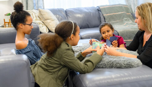 Family-friendly game Kids sitting on a living room floor playing cards together, enjoying a fun game similar to andar bahar.