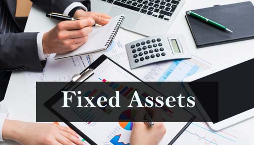 Non-current or fixed assets Office workspace with a focus on financial documents, a calculator, and charts, with the text'Fixed Assets' indicating a focus on asset management.