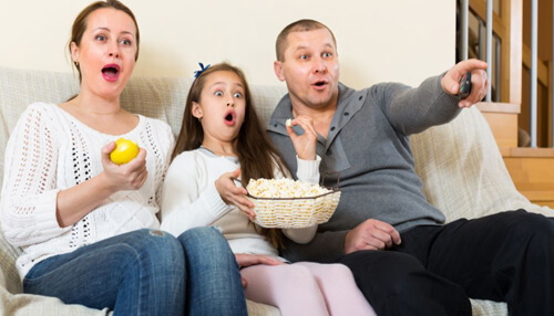 Home entertainment market A family enjoying a tv show together, with surprised expressions while watching, highlighting the entertainment experience of watching tv shows.