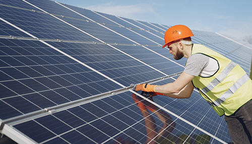 Solar panels - tycoonstory | tycoonstory media A worker in safety gear adjusting solar panels, representing the installation process that can be supported through solar financing options for businesses and homeowners