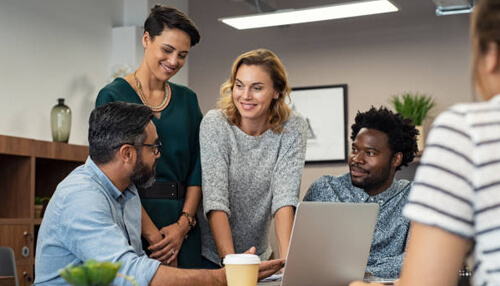 Wearing business casual attire - tycoonstory | tycoonstory media Team of professionals dressed in business casual attire collaborating around a laptop, demonstrating modern and stylish office wear for a business setting.