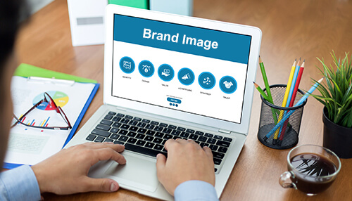 A credible brand image - tycoonstory | tycoonstory media Person typing on a laptop displaying a "brand image" slide, which includes the design of business cards.