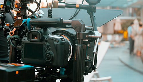 Beautiful places - tycoonstory | tycoonstory media A professional camcorder on a tripod, with an external monitor displaying a live feed, positioned within a brightly lit studio setting. Essential video production gear in a broadcast studio.