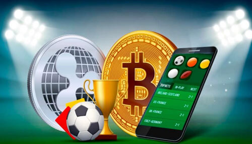 Betting with cryptocurrencies - tycoonstory | tycoonstory media Betting with cryptocurrencies: mobile app, golden trophy, soccer ball, logos of bitcoin and ripple under stadium light.