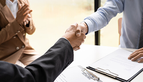 Check references and backgrounds Close-up of a handshake between an employer and employee during interviews, representing a successful hiring agreement.
