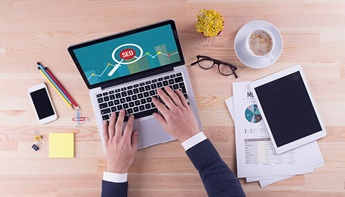 Marketing using seo A person working on a laptop displaying detailed analytics and bar graphs, tracking the global market performance of an expanding business empire.