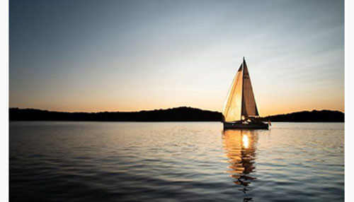 Motley fools stock picking services A sailboat on calm water at sunset, symbolizing financial freedom often promoted by the motley fool.