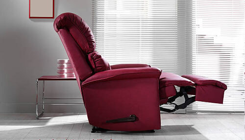 Recliner - tycoonstory | tycoonstory media Luxurious red recliner chair extended for relaxation in a modern living room setting.