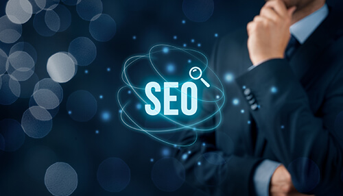 Search engine optimization Seo and web design concept with suited businessperson amidst blur of bokeh lights, featuring word'SEO' with magnifying glass as centerpiece.
