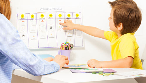 Set schedules A child interacting with a weekly calendar while a parent guides them, possibly planning educational activities related to children's internet usage.