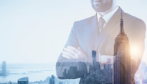 Business professional standing with arms crossed, overlayed with a cityscape, symbolizing self-employment and success through entrepreneurial development programs Businessman standing confidently with arms crossed, overlaying a city skyline, symbolizing growth through entrepreneurial development programs.