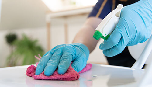 Successful cleaning training program Worker disinfecting a surface with gloves and spray bottle during cleaning training.