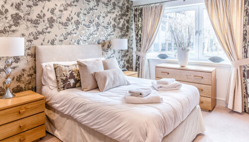 Wallpaper for your bedroom Cozy bedroom featuring a double bed, soft linens, floral wallpaper, and natural daylight.