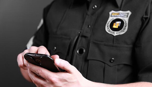 Security company Security company officer in uniform using a mobile phone, representing service details, pricing transparency, and what is included in security company packages.