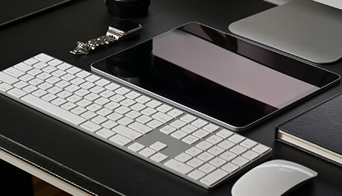 What are the benefits of leather accessories A close-up of a minimalist office desk with a keyboard, tablet, and mouse, highlighting a clean and organized workspace.