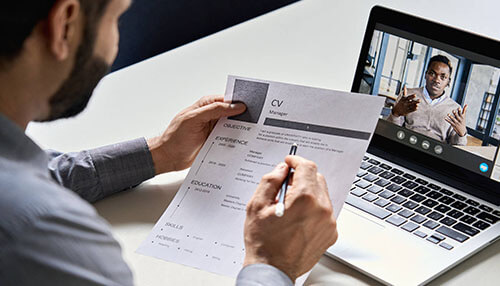 Why you need to hire via video interviewing Hiring manager reviewing a candidate’s cv during a video interviewing session on a laptop