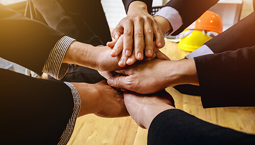 Empower your employees Hands of employees stacked together showing collaboration and team spirit, highlighting employee engagement.