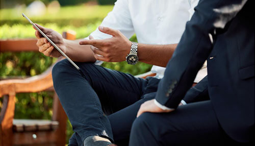 Establish your core business model Two professionals sitting outdoors, discussing a tablet, representing a business conversation or collaboration.