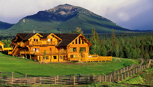 Hidden valley ranch house Scenic view of a wooden ranch house surrounded by mountains, ideal for vacation rentals in a serene natural setting.