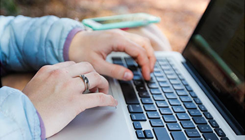Learn in the flow of work Learning in the flow of work shown by hands typing on a laptop outdoors, representing continuous learning, skill development, and productivity during everyday work tasks.