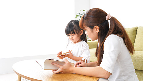 Signs to look out for Mother helping her child with a book at home, offering support for learning disabilities through guided learning.