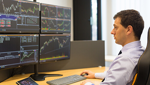 Trade instrument A trader analyzing multiple charts on several monitors in an office, monitoring price movements and trends in the forex market.