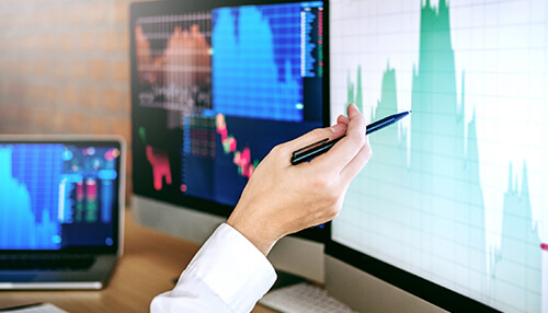 Binary option trading Trader analyzing market graphs on multiple monitors for binary option trading analysis.
