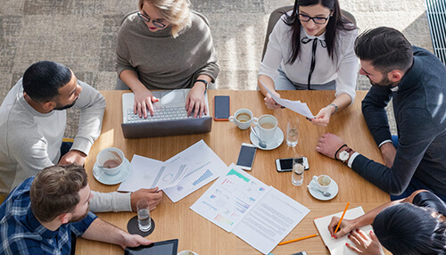A diva diverse starting team is essential for successerse starting team is essential for success - tycoonstory | tycoonstory media A work team collaborating around a table with documents, laptops, and coffee cups during a meeting.