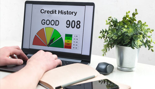 Credit history A person using a laptop showing a credit score chart labeled ‘good 908,’ representing the importance of credit history when applying for a personal loan.