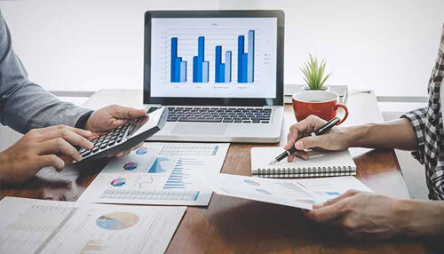 Increases your company's Equity Two professionals discussing business data and graphs on paper and a laptop, focusing on business process improvement and strategic decision-making.