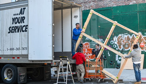 Hiring a moving company Workers unloading large items from a moving truck and setting up a structure, showcasing teamwork and professional moving services.