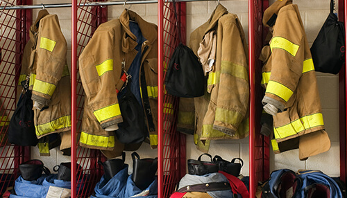 Firefighters Firefighter uniforms and gear hanging in lockers, representing practical and thoughtful gifts for firefighters who serve on duty.