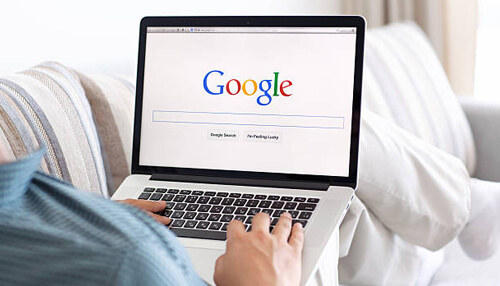 Benefit from google searches Person using a laptop to browse the google search homepage, representing the reach of a custom website.