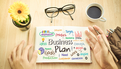 Create a business plan Image of a business plan notebook with keywords like'business', 'goals', 'marketing', 'target', and 'teamwork' written in colorful text, symbolizing the process of creating a business plan.