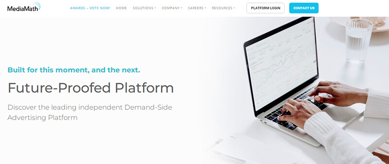 Mediamath Mediamath homepage featuring a person typing on a laptop displaying charts and analytics, alongside the text future-proofed platform.